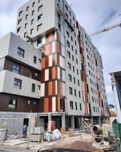 Fachada Edificio Torres Las Palmas, revestimiento en gris y marrón, persianas naranjas, rojas, marrones y crema.