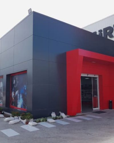 Fachada Nave Würth, revestimiento en negro y entrada a la tienda en rojo
