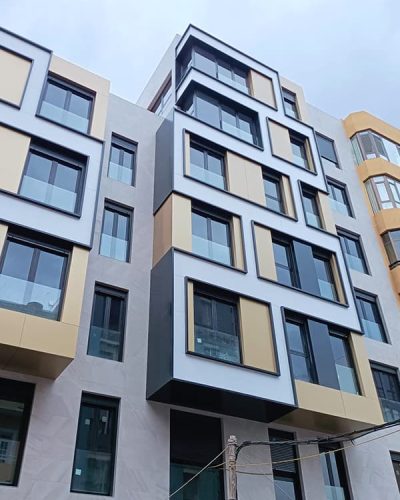 Revestimiento de fachada en gris con detalles de la zona cajas de ventanas en negro, dorado y blanco