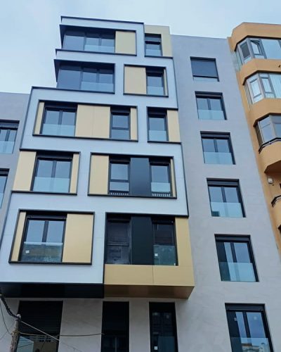 Revestimiento de fachada en gris con detalles de la zona cajas de ventanas en negro, dorado y blanco