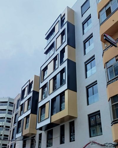 Revestimiento de fachada en gris con detalles de la zona cajas de ventanas en negro, dorado y blanco